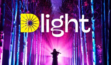 Person plays the violin on a glowing, purple-lit forest path at TreeChurch and Gardens under a starry sky.
